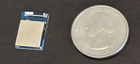 nRF52840 microcontroller, next to a quarter for scale.